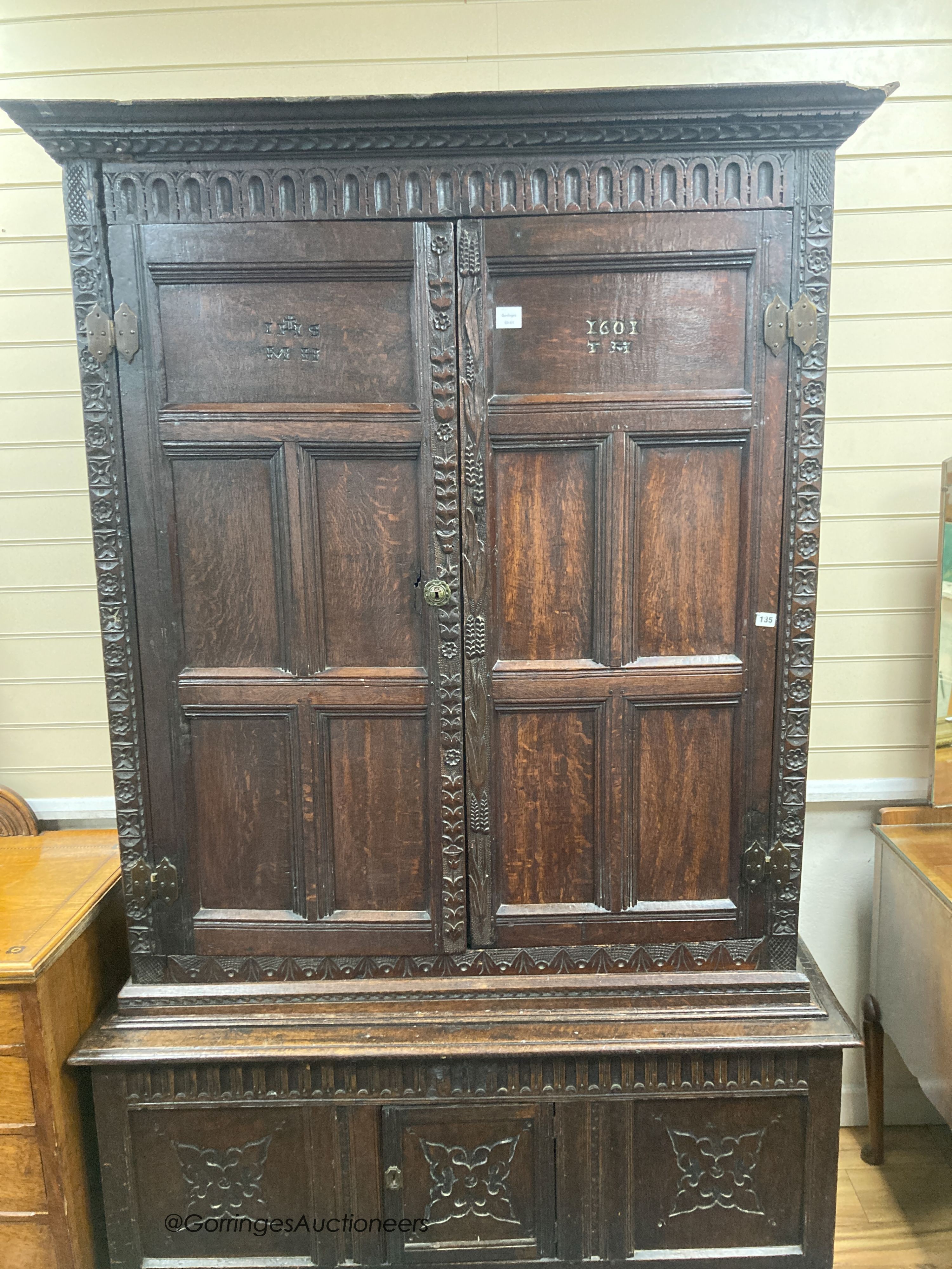 A carved oak cupboard, enclosed by panelled doors, bearing monograms and dated 1601, width 138cm, depth 53cm, height 218cm